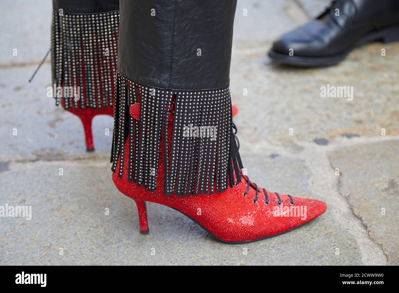 MILAN, ITALY - SEPTEMBER 26, 2020: Woman with red glitter high heel shoes and leather trousers with fringes before Philosophy fashion show, Milan Fash Stock Photo