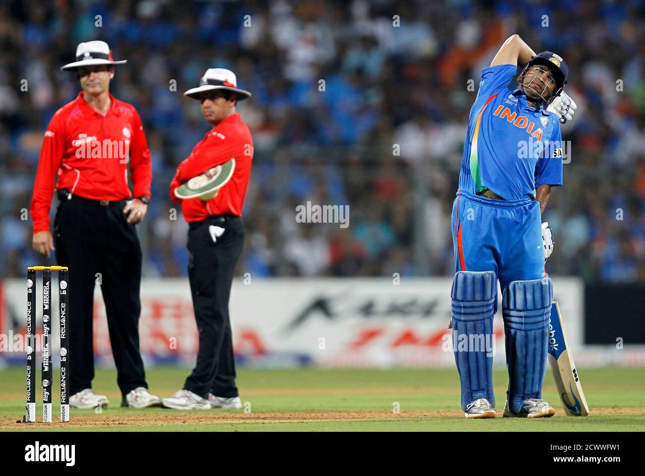 India's captain Mahendra Singh Dhoni (R) stretches as umpires Aleem Dar and Simon Taufel (L) stand together during their ICC Cricket World Cup final match against Sri Lanka in Mumbai April 2, 2011.                      REUTERS/Adnan Abidi (INDIA  - Tags: SPORT CRICKET) Stock Photo