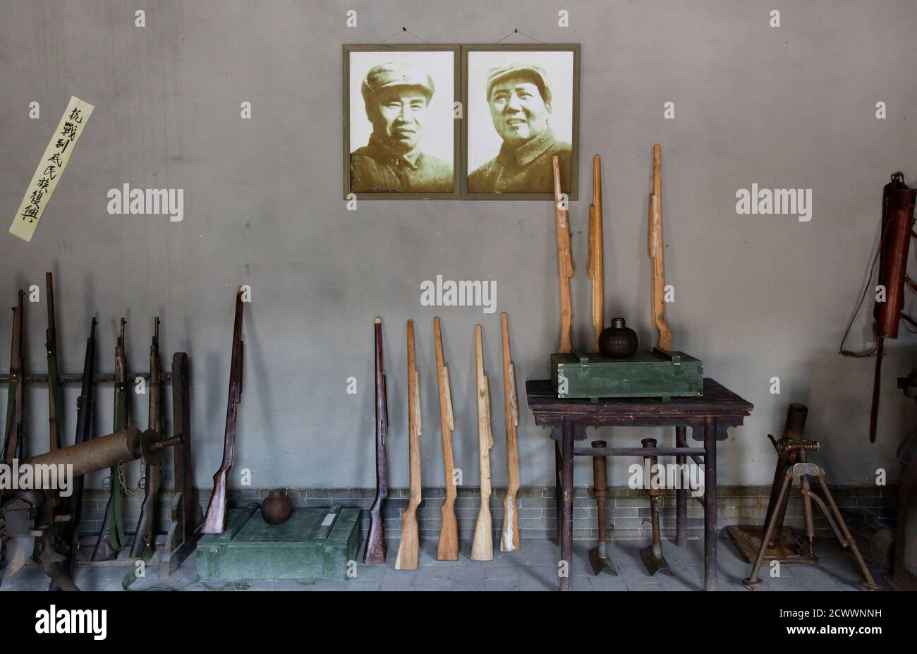 Wooden guns are placed next to portraits of late Chairman Mao Zedong (R) and late commander-in-chief Zhu De at the Eighth Route Army Culture Park, one of two theme parks, in Wuxiang county, north China's Shanxi province, October 20, 2012. Visitors to the theme parks pay to participate in a dress up action play with performers, where they can choose to role play as soldiers from the Japanese army or the Eighth Route Army, with professional sound and lighting effects. A live-action show and the parks, located near the former headquarters of the Eighth Route Army, a military group controlled by t Stock Photo