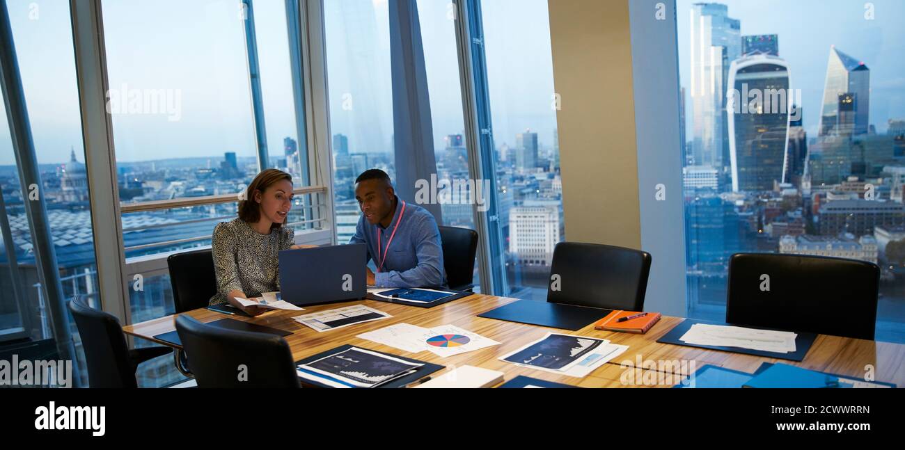 Business people working at laptop in highrise conference room meeting Stock Photo