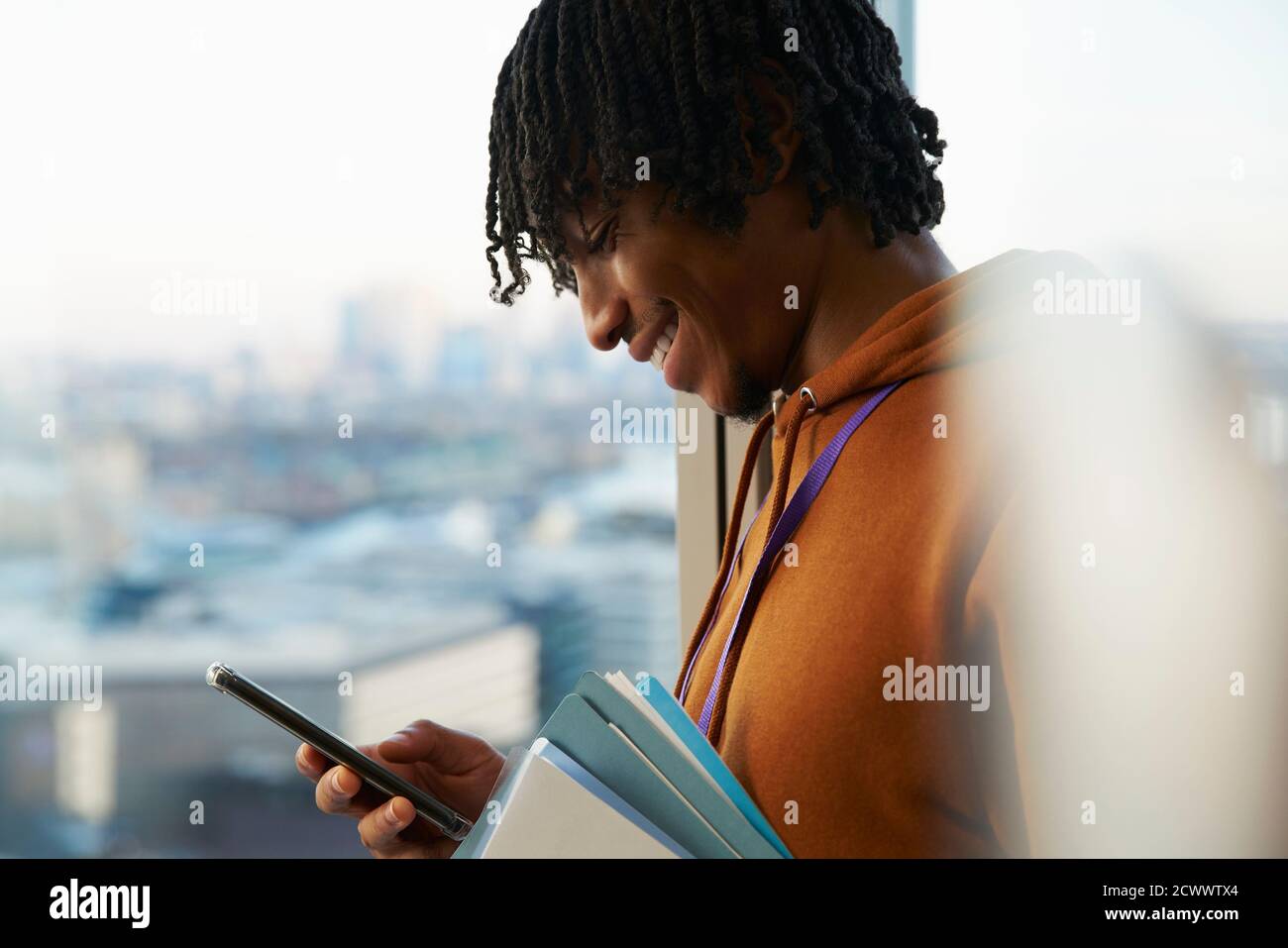 Smiling businessman using smart phone at window Stock Photo
