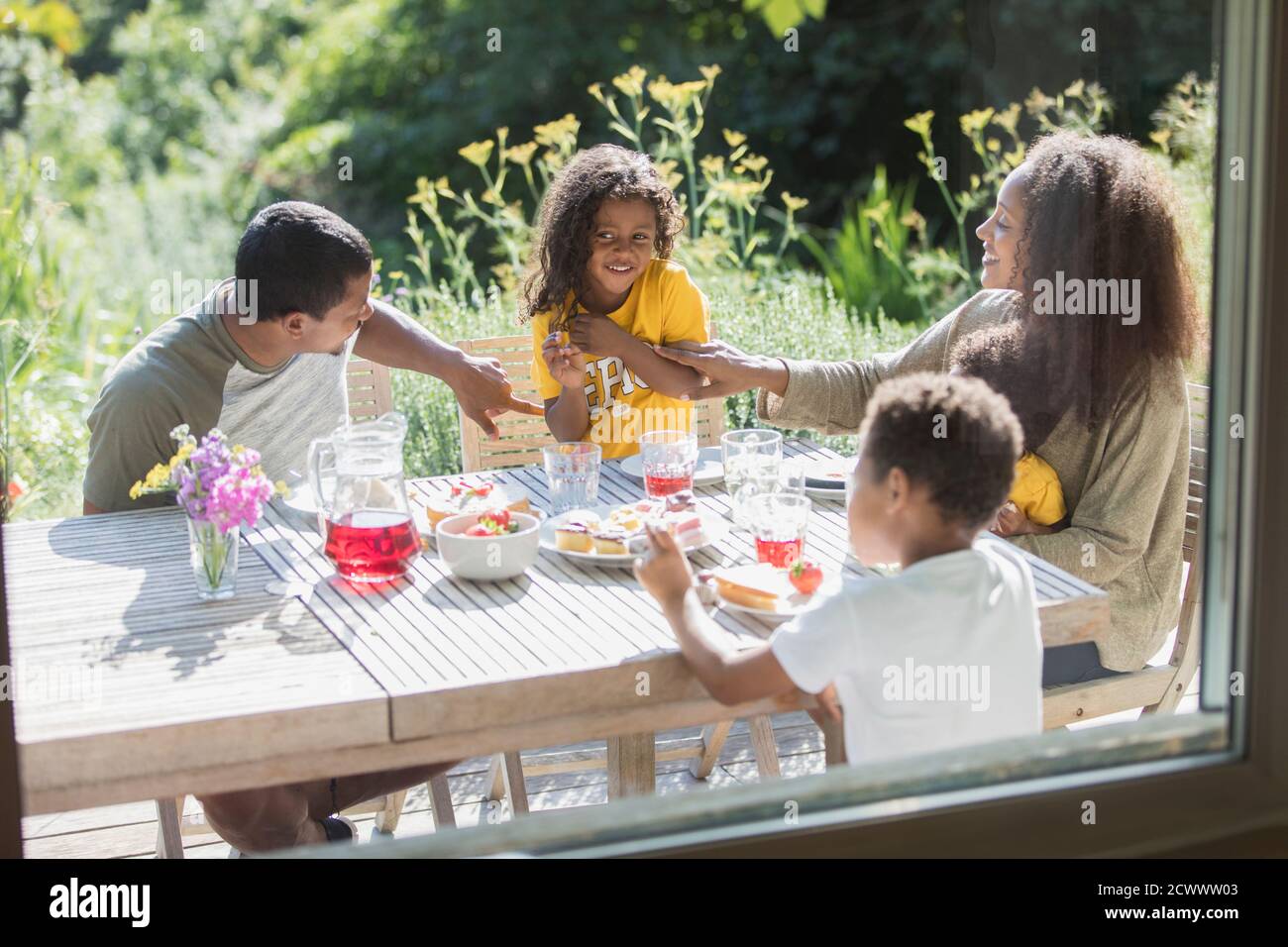 Happy family enjoying lunch on sunny summer patio Stock Photo