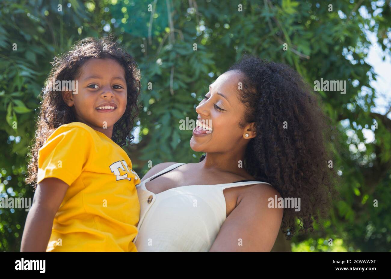Portrait happy mother and daughter under tree in summer park Stock Photo