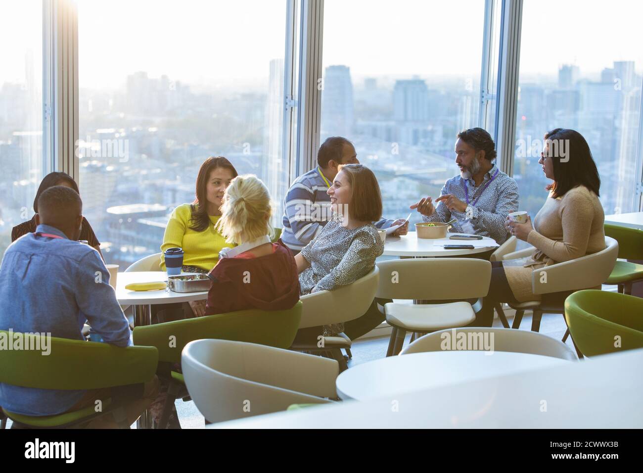 Business people eating lunch and socializing in highrise cafeteria Stock Photo
