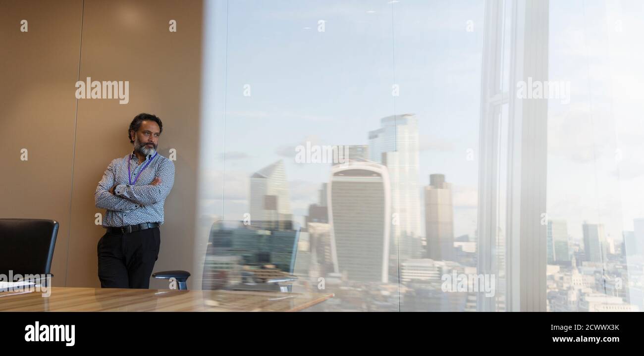 Thoughtful businessman in highrise urban conference room Stock Photo