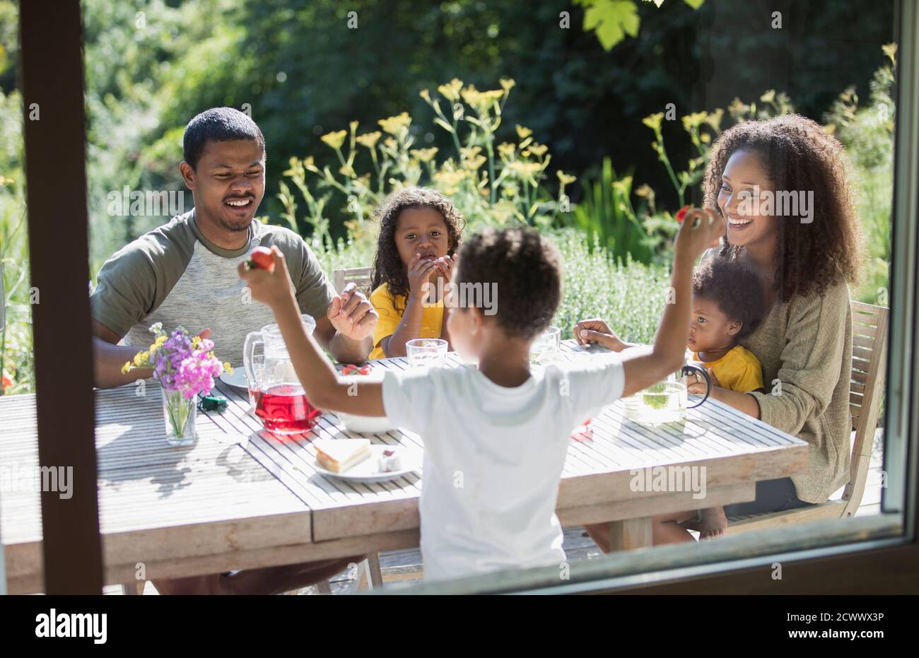 Happy family enjoying garden lunch on sunny summer patio Stock Photo