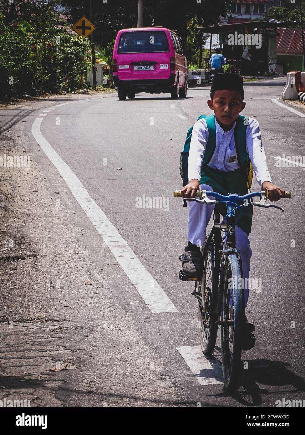 Teenage boy driving bicycle by the side of the road Stock Photo