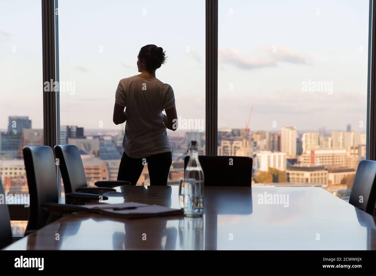 Thoughtful businesswoman looking out highrise office window Stock Photo
