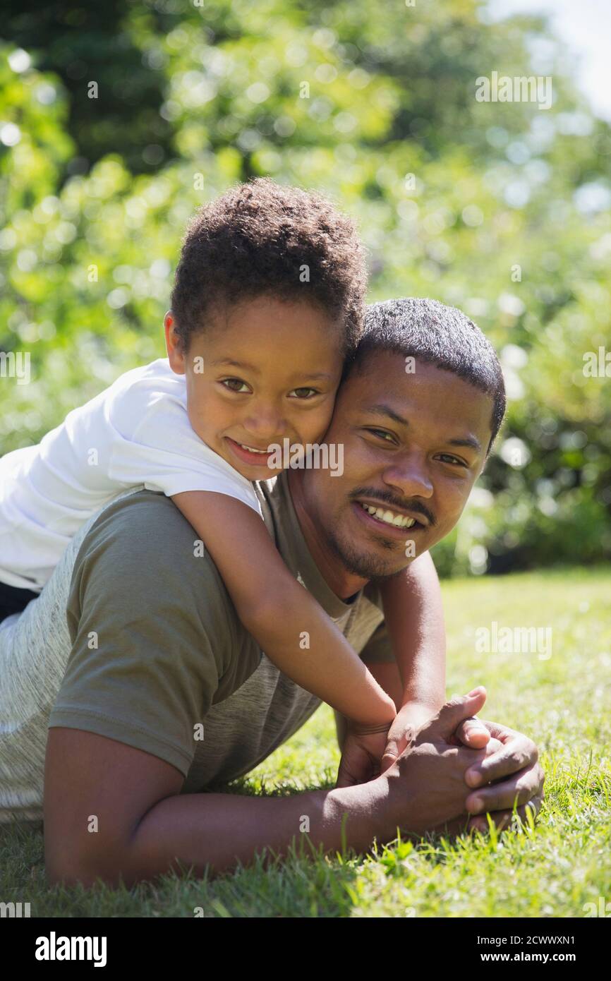 Portrait happy father and son hugging in sunny summer grass Stock Photo ...