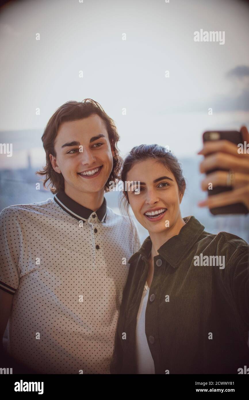 Happy young couple taking selfie with camera phone at window Stock Photo