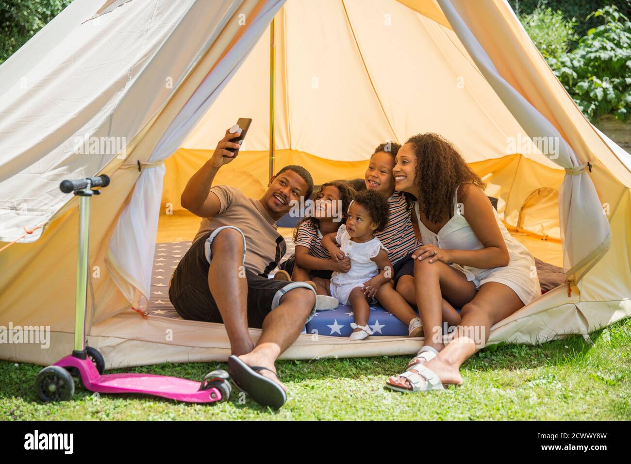 Happy family taking selfie with camera phone inside summer tent Stock Photo