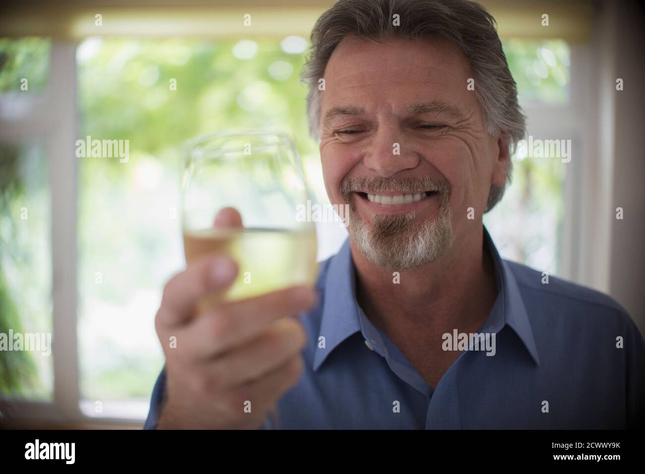 Close up smiling senior man drinking white wine Stock Photo
