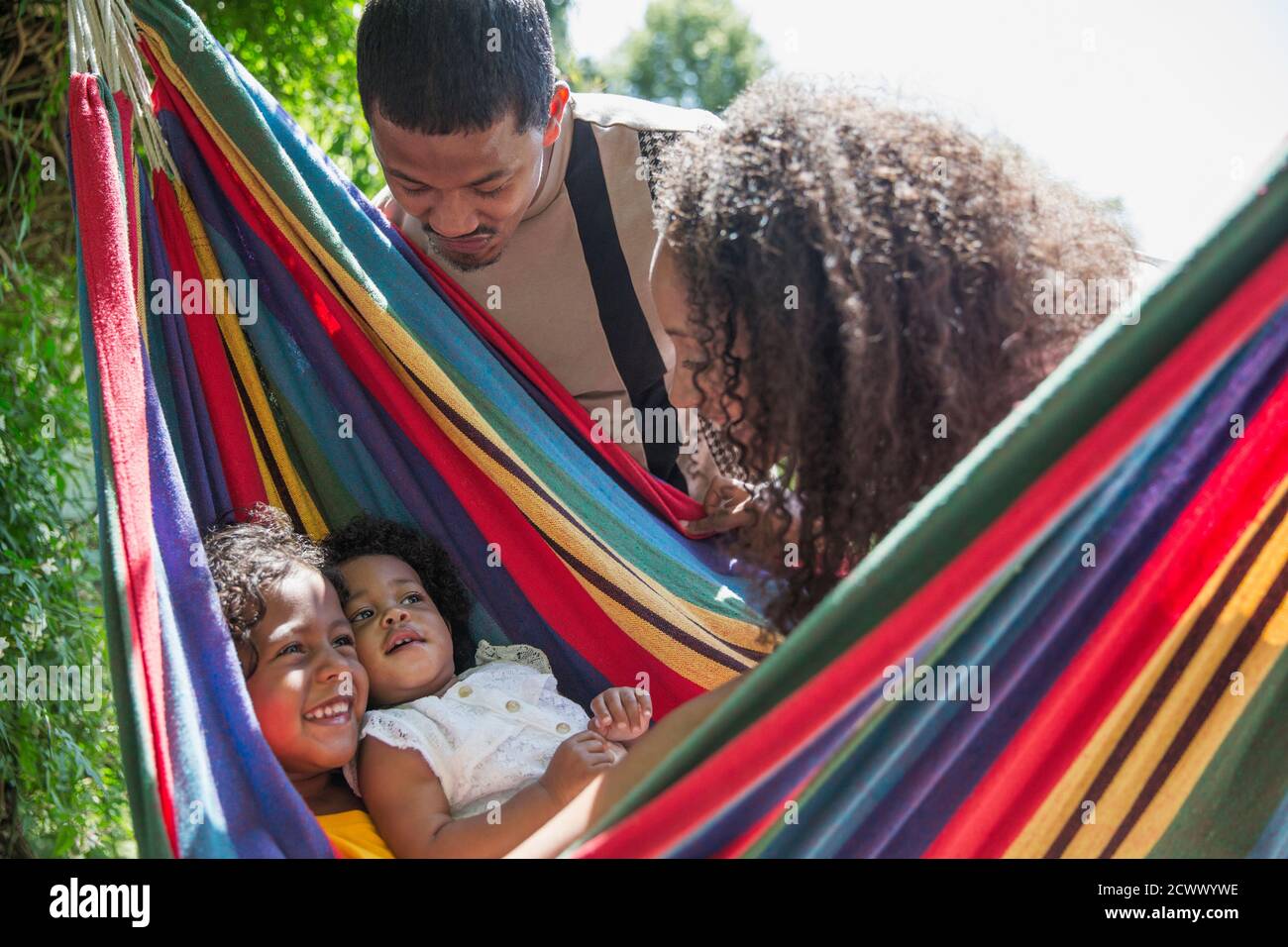 Parents watching happy daughters in sunny summer hammock Stock Photo