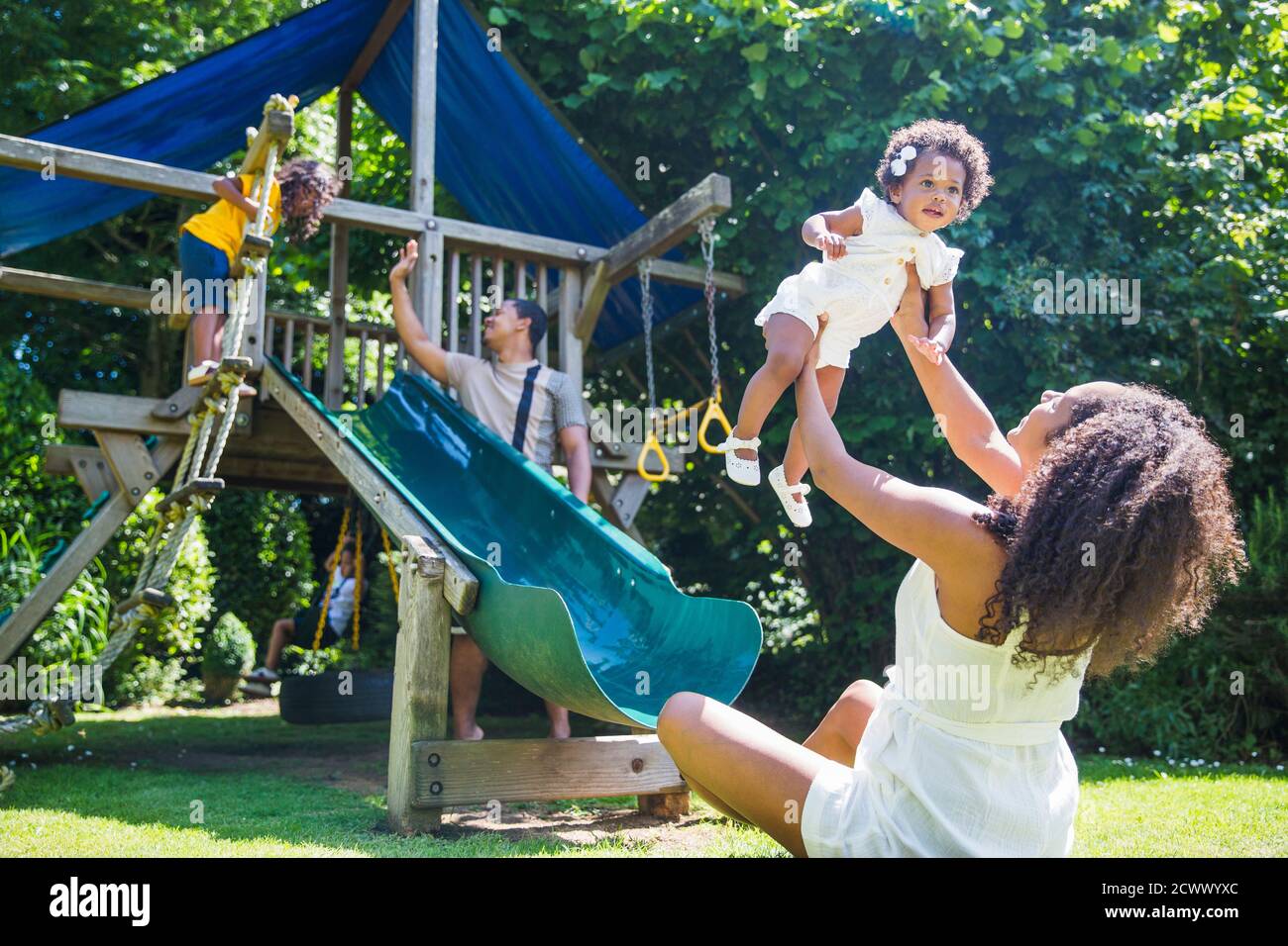 Happy family playing at playground set in sunny summer backyard Stock Photo
