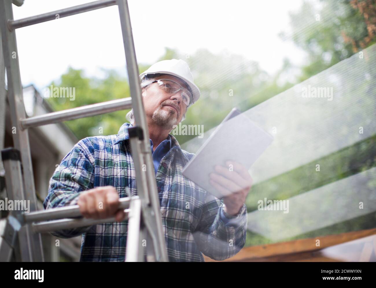 Senior male construction foreman using digital tablet on ladder Stock Photo