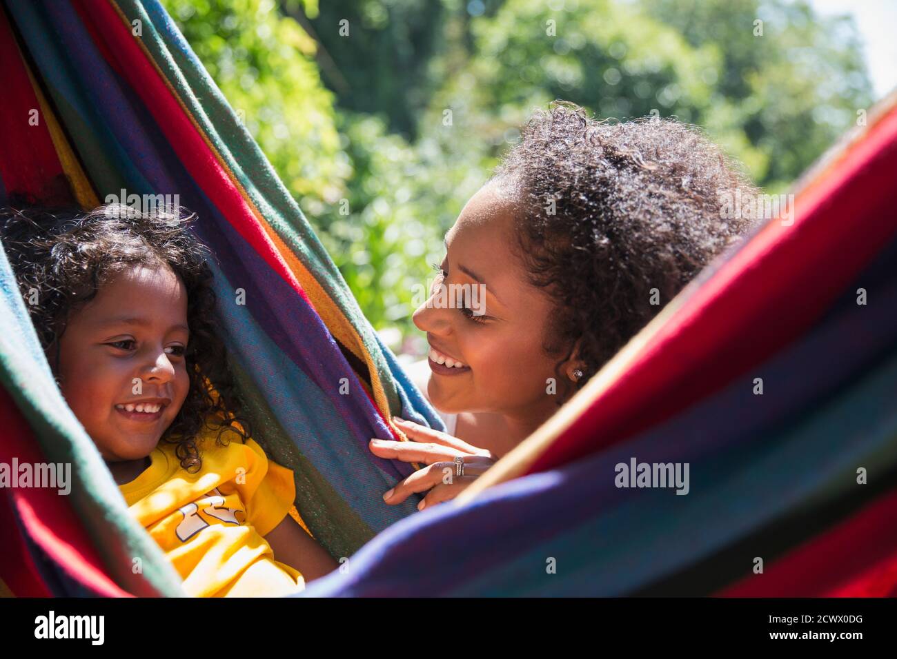 Happy mother watching daughter in sunny summer hammock Stock Photo