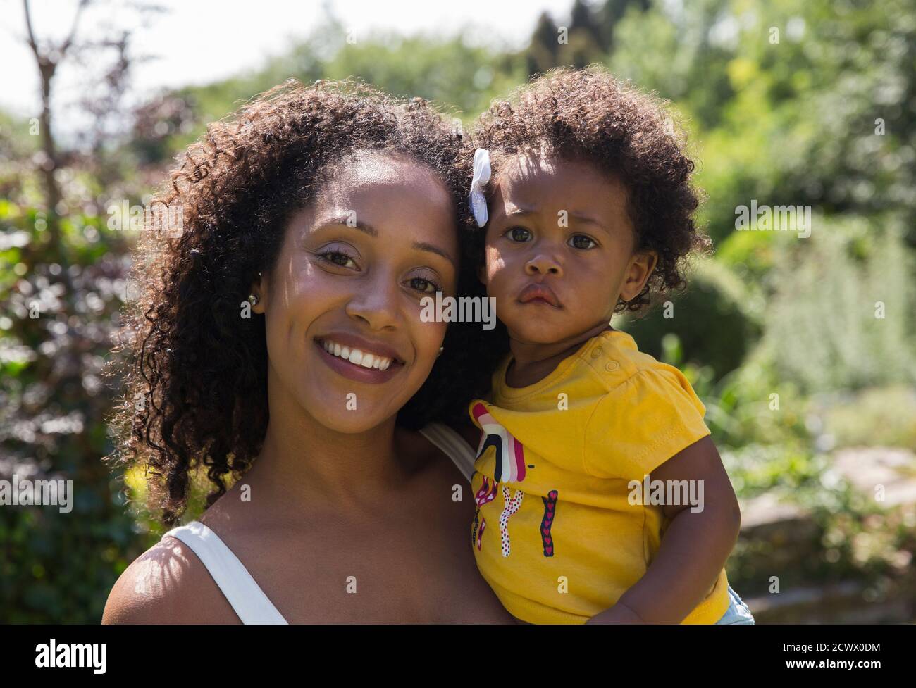 Portrait happy mother and toddler daughter in sunny yard Stock Photo
