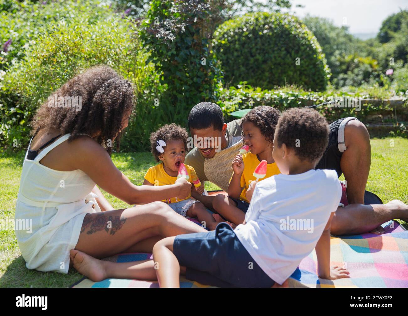 Happy family eating watermelon popsicles in sunny summer backyard Stock Photo