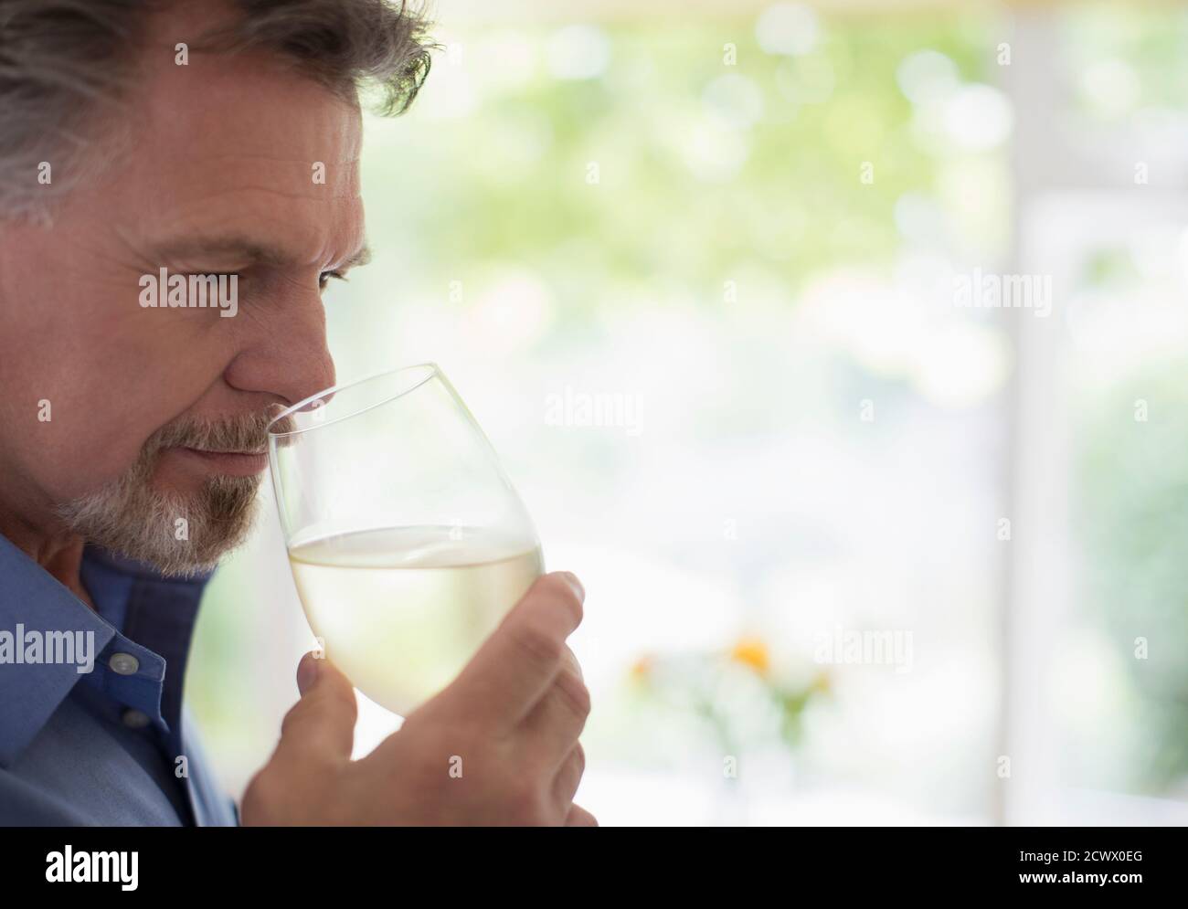 Close up senior man smelling and tasting white wine Stock Photo