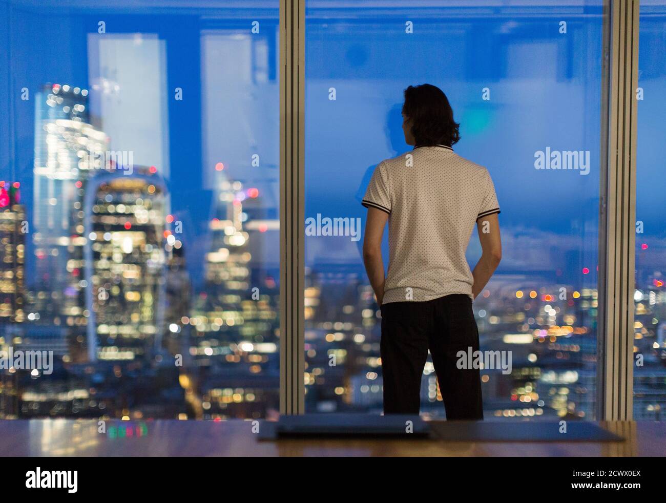 Thoughtful businessman working late at highrise window, London, UK Stock Photo