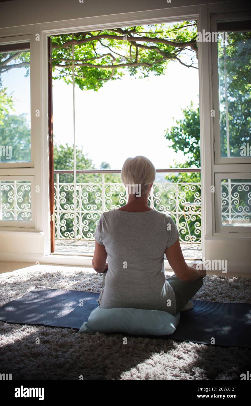 Serene senior woman meditating at tranquil summer balcony doorway Stock Photo