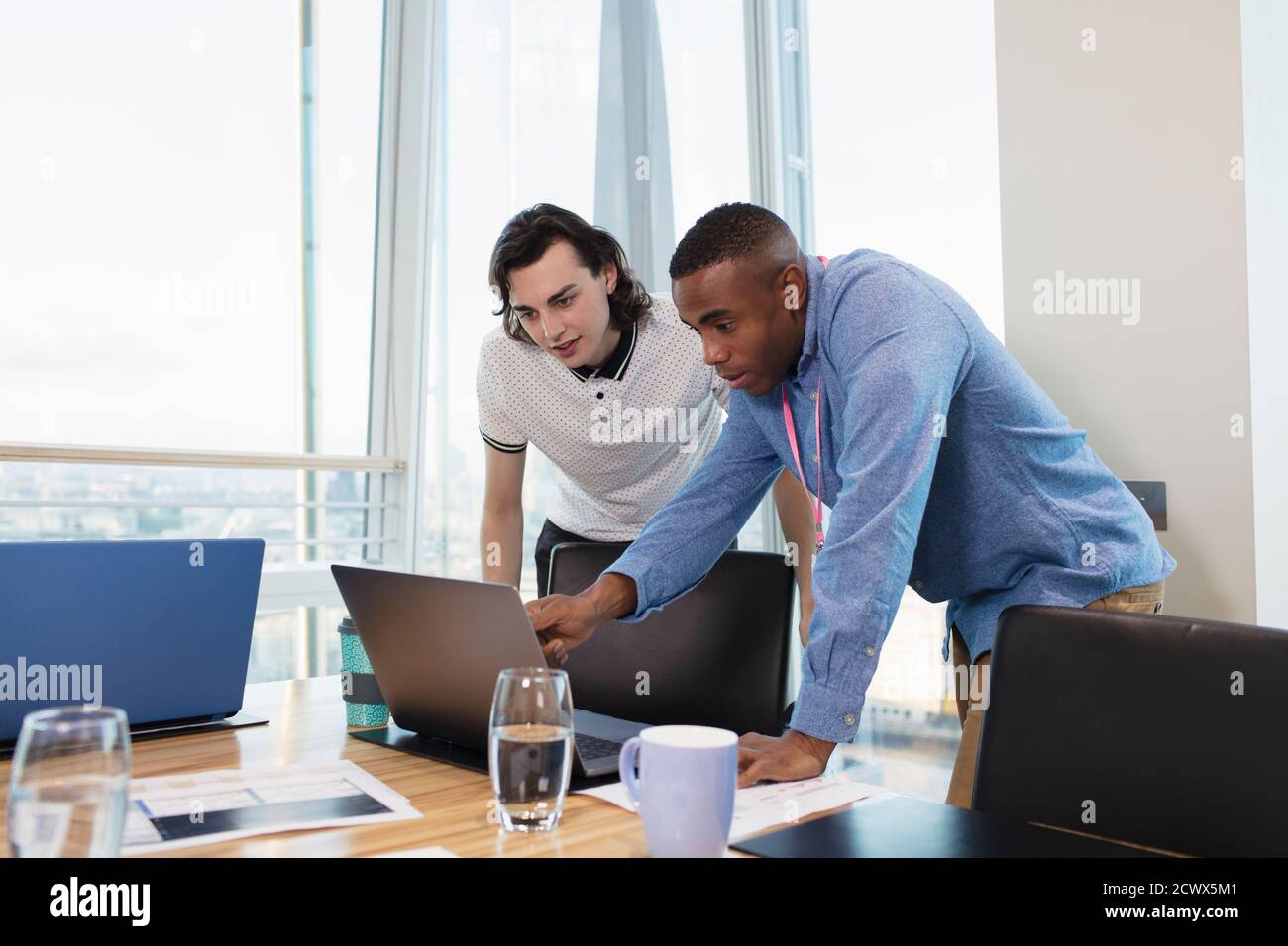 Businessmen working at laptop in conference room Stock Photo