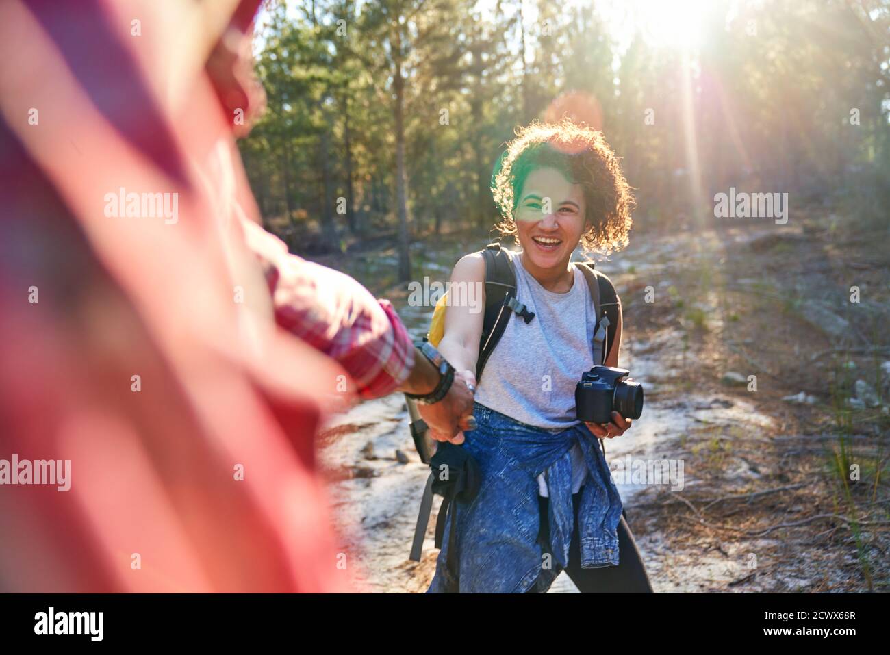 Happy young couple hiking with camera in sunny woods Stock Photo