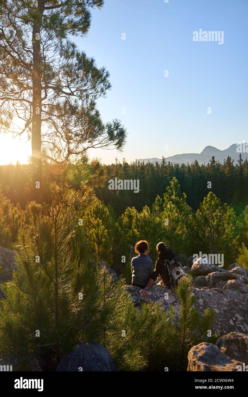Young hiker couple enjoying sunny view of trees in woods at sunset Stock Photo