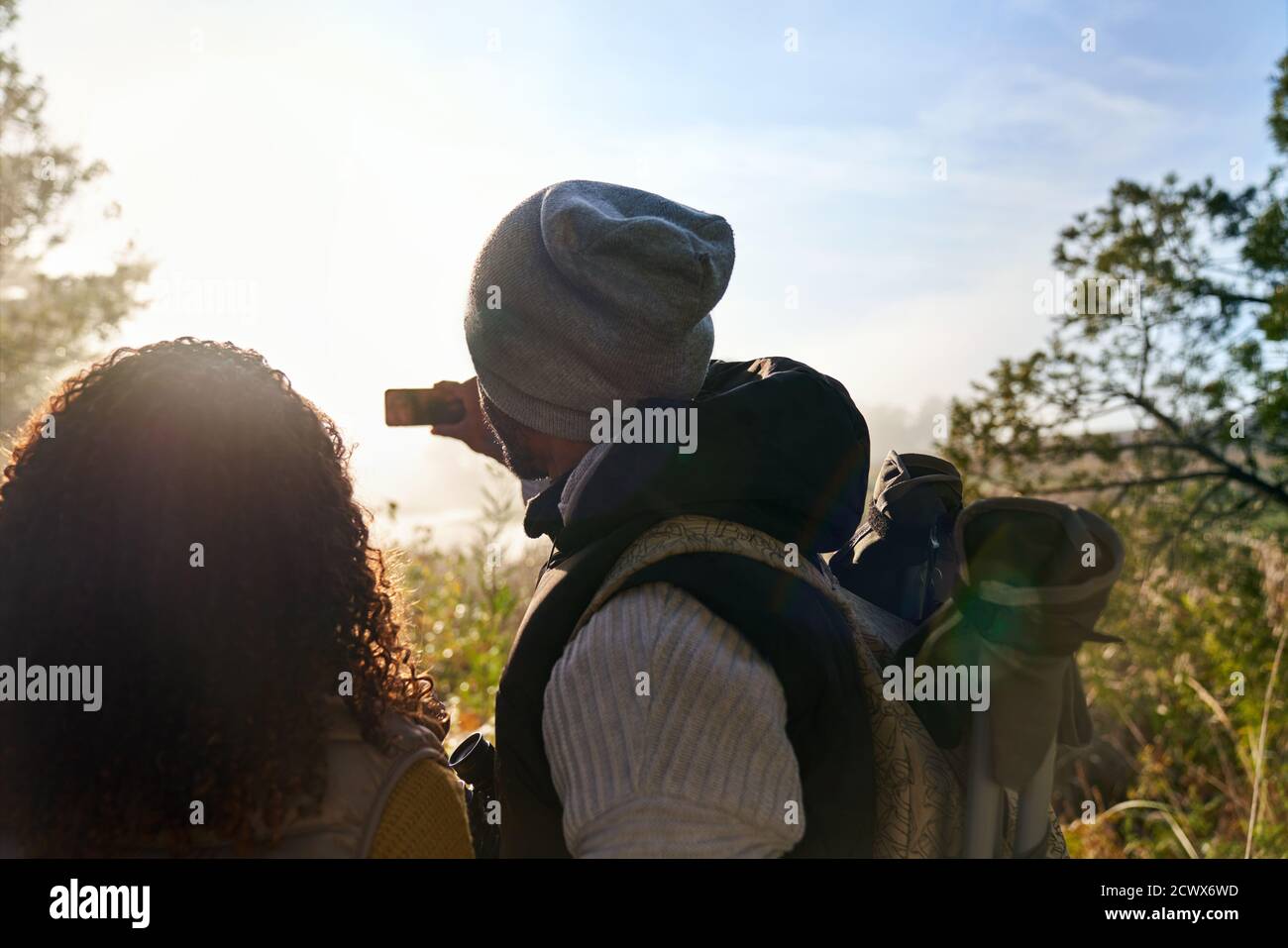 Young couple hiking and using camera phone in sunny woods Stock Photo