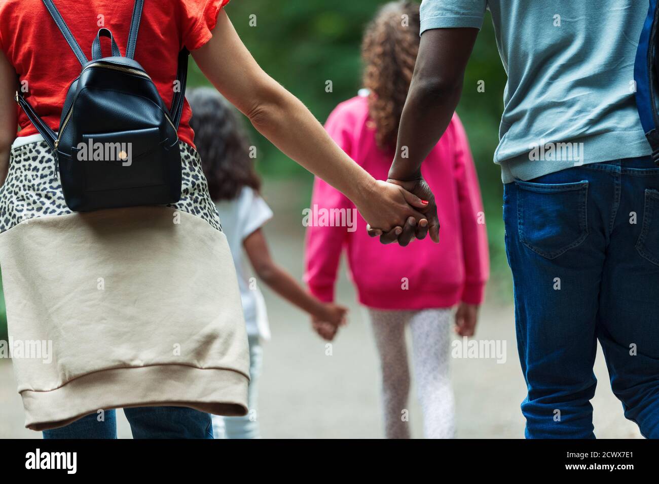 Affectionate family holding hands and walking on path Stock Photo