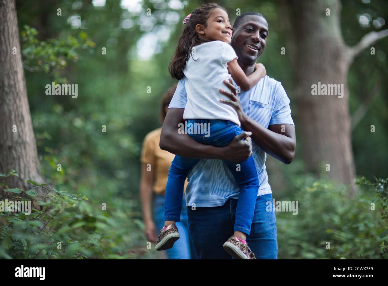 Happy father carrying daughter on hike in woods Stock Photo
