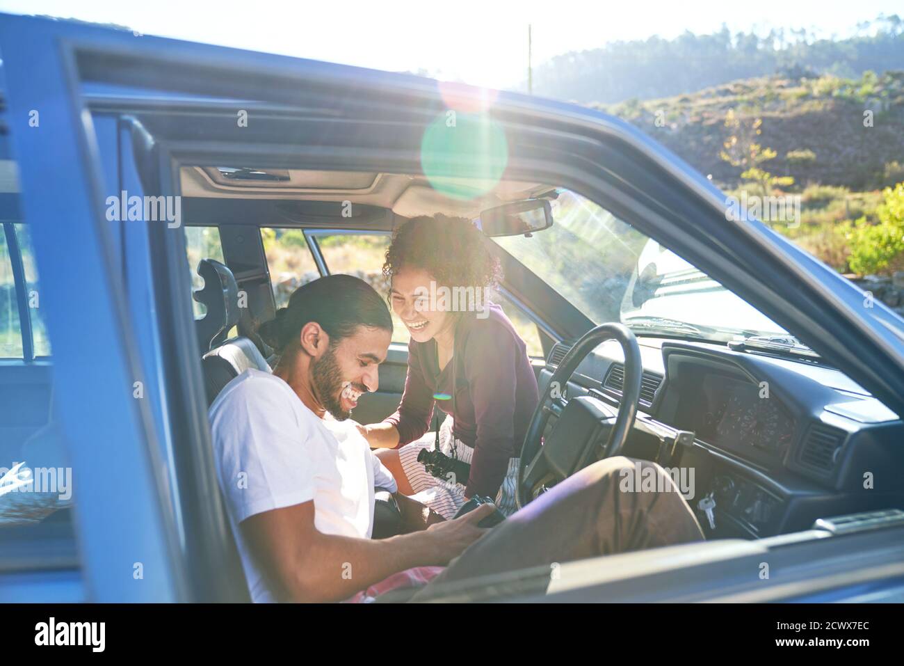 Happy young couple laughing on road trip in sunny car Stock Photo