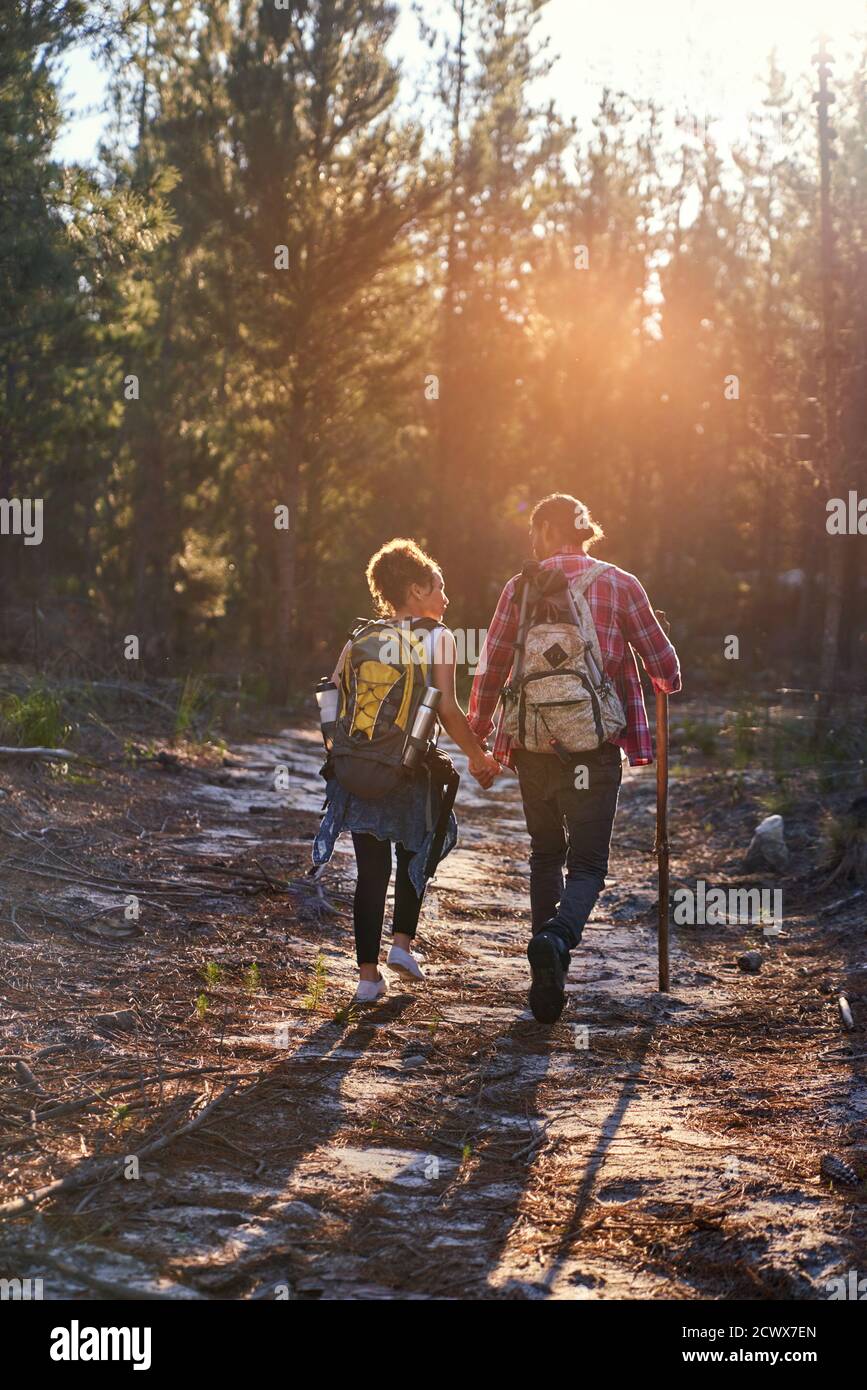 Young couple with backpacks hiking in sunny woods Stock Photo