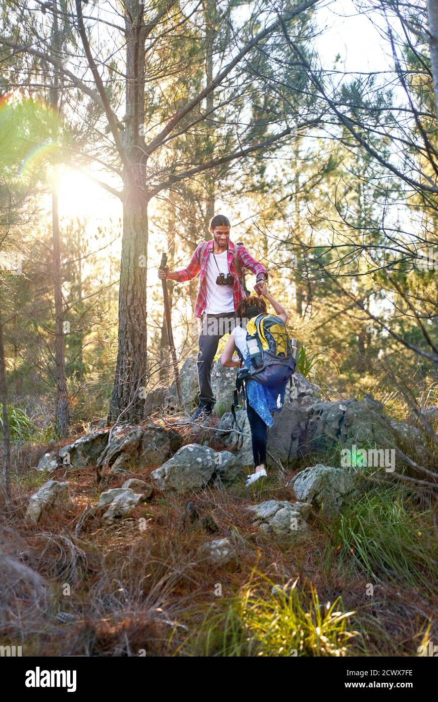 Young couple hiking up slope in sunny woods Stock Photo