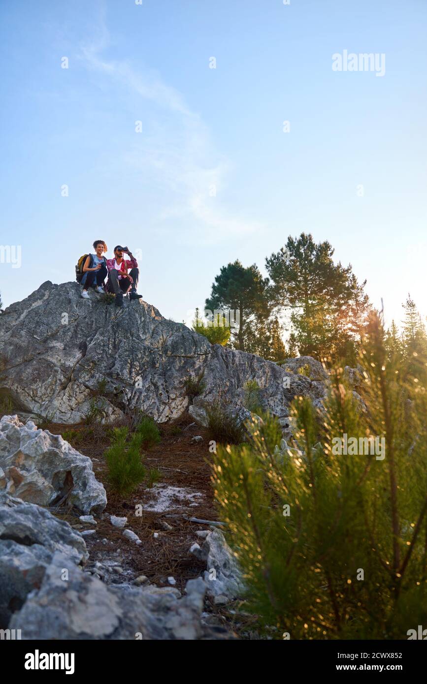 Young couple with binoculars on rock in nature Stock Photo