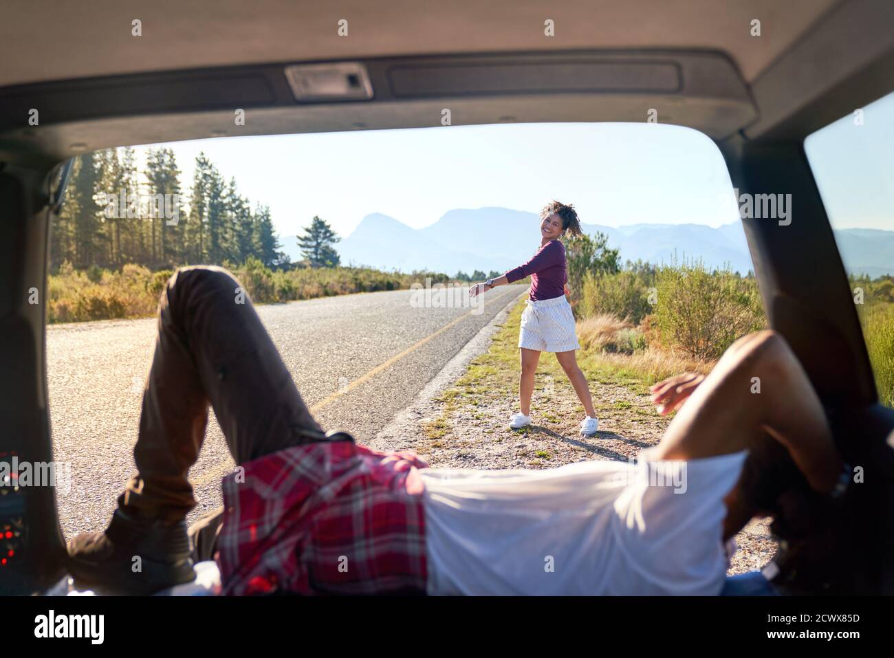 Happy carefree couple relaxing outside car at sunny remote roadside Stock Photo
