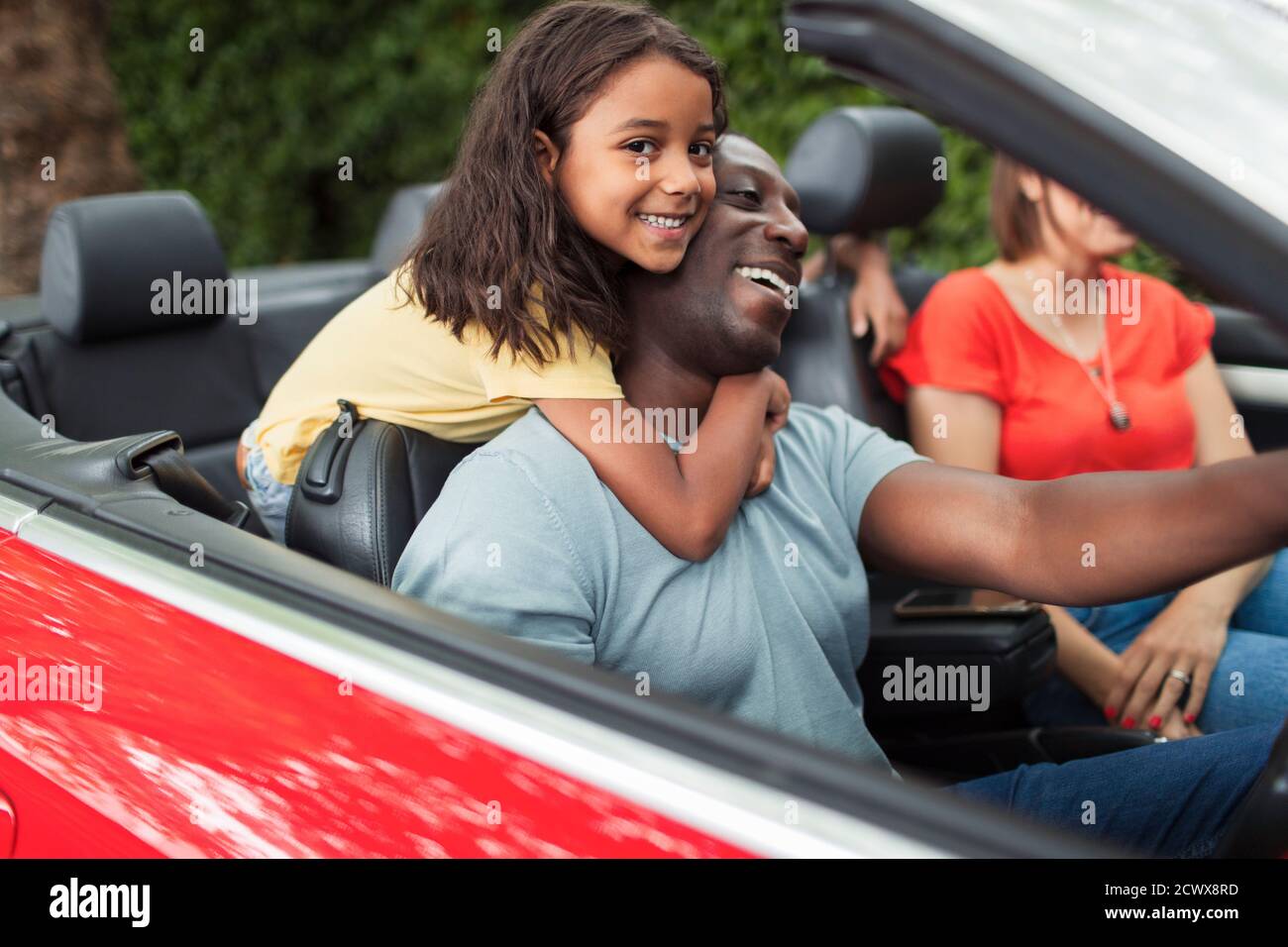 Portrait happy daughter hugging father driving convertible Stock Photo
