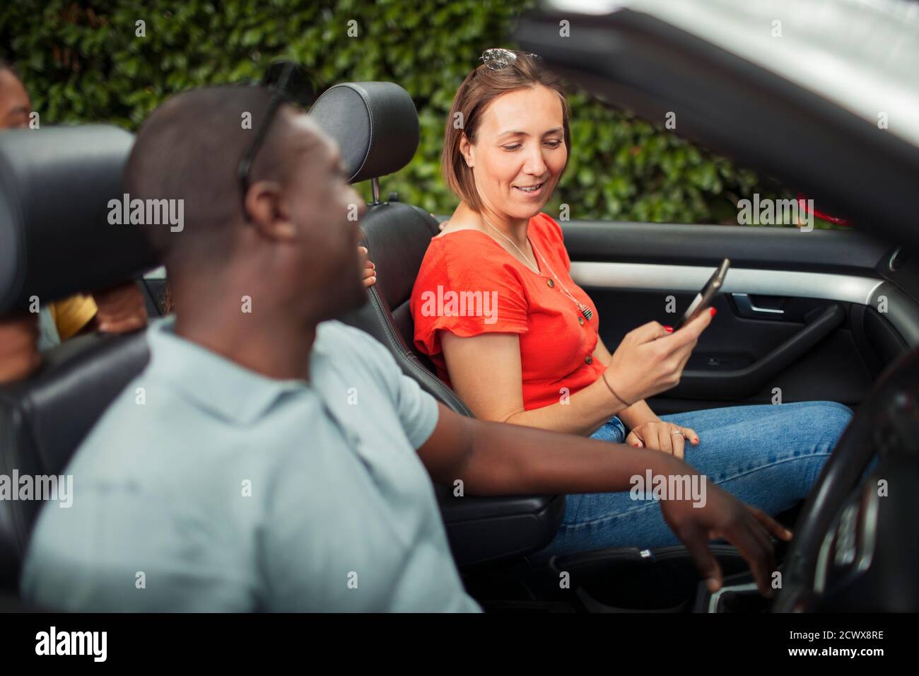 Couple using smart phone in convertible Stock Photo