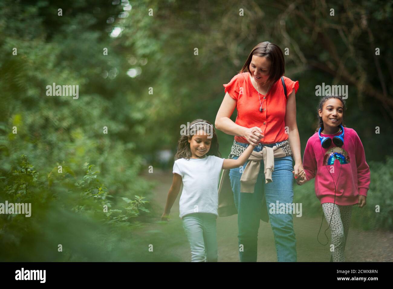 Mother and daughters hiking on trail in woods Stock Photo