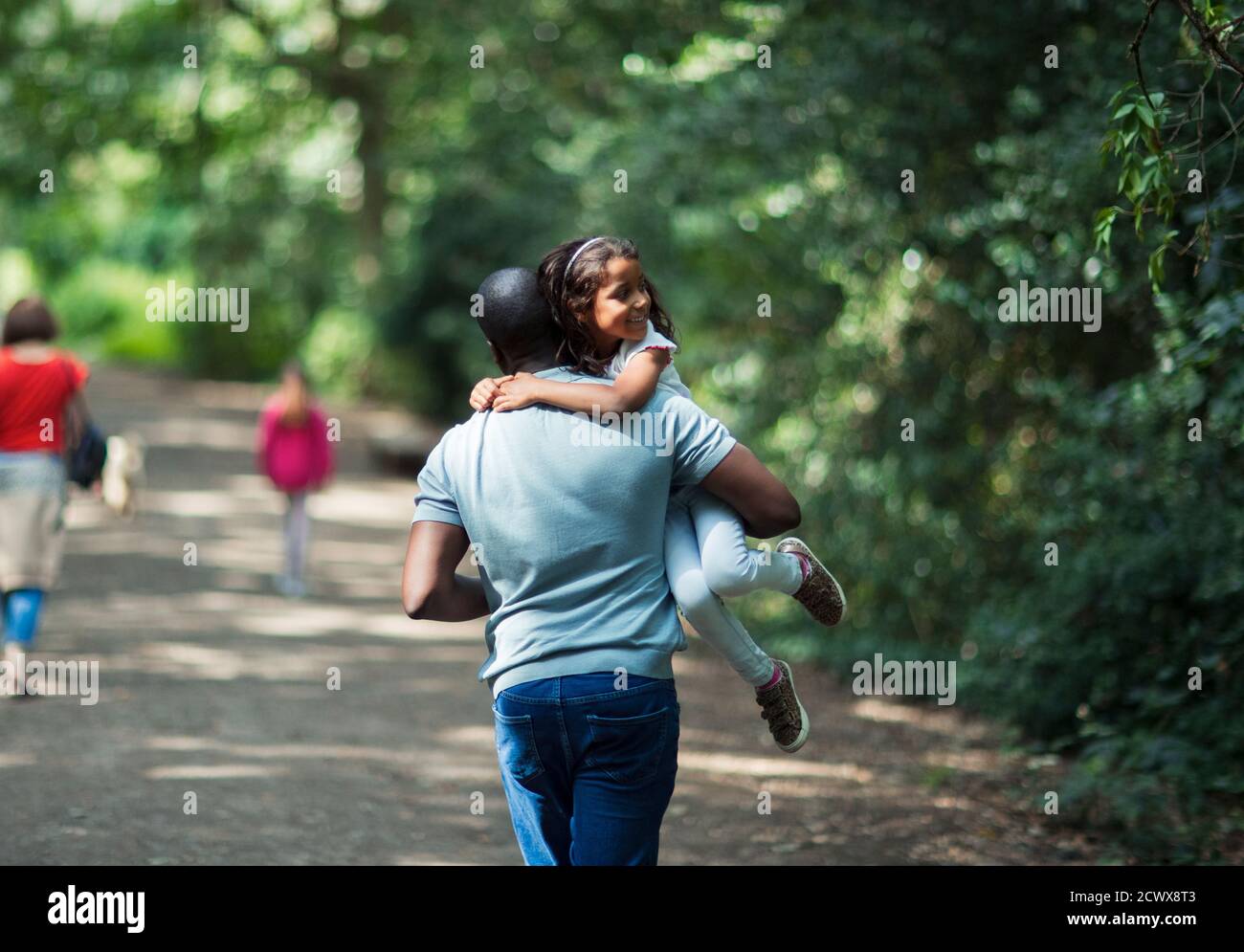 Playful father carrying happy daughter on trail in woods Stock Photo