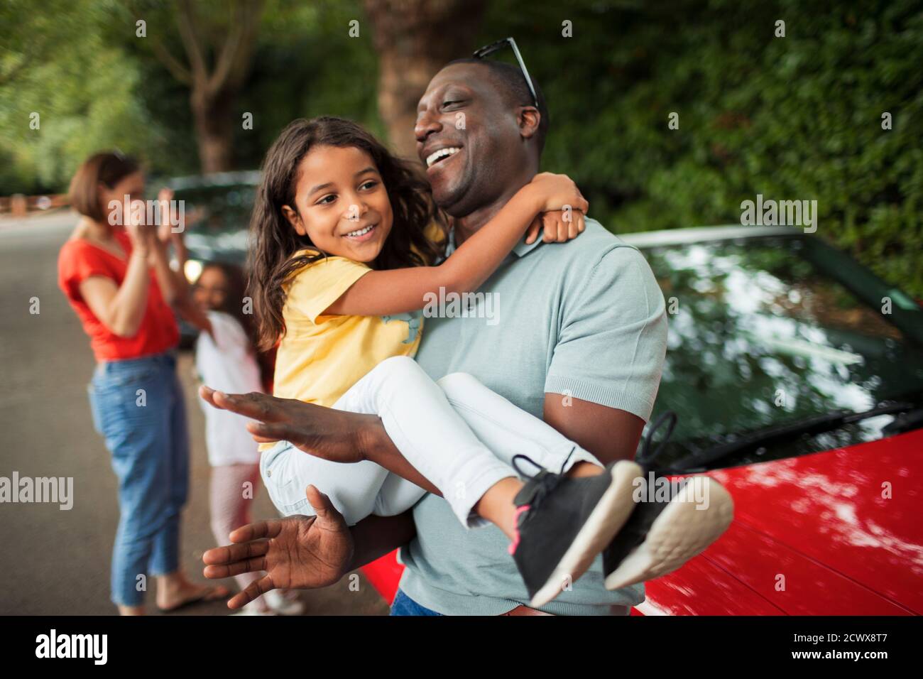Happy father holding daughter outside convertible Stock Photo