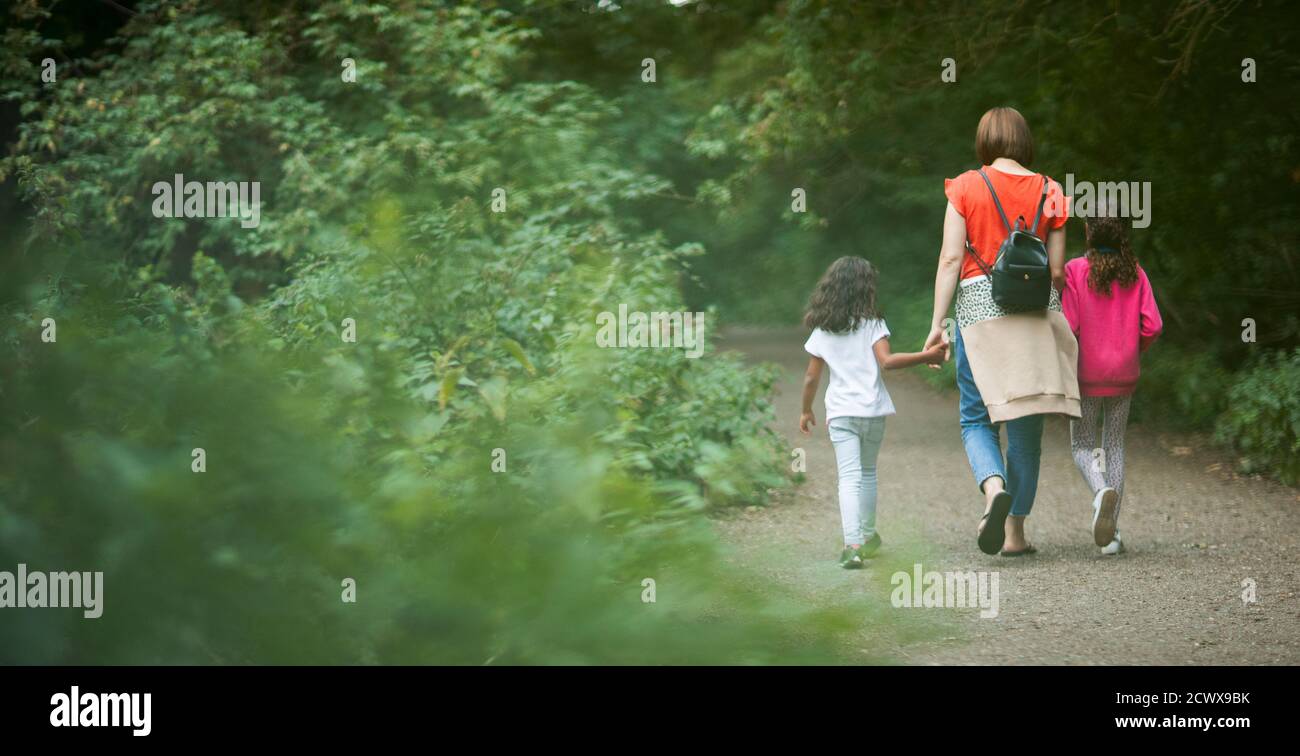 Mother and daughters hiking on path in woods Stock Photo