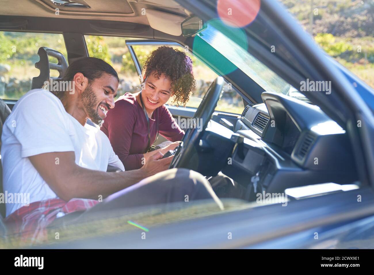 Happy young couple enjoying road trip in sunny car Stock Photo