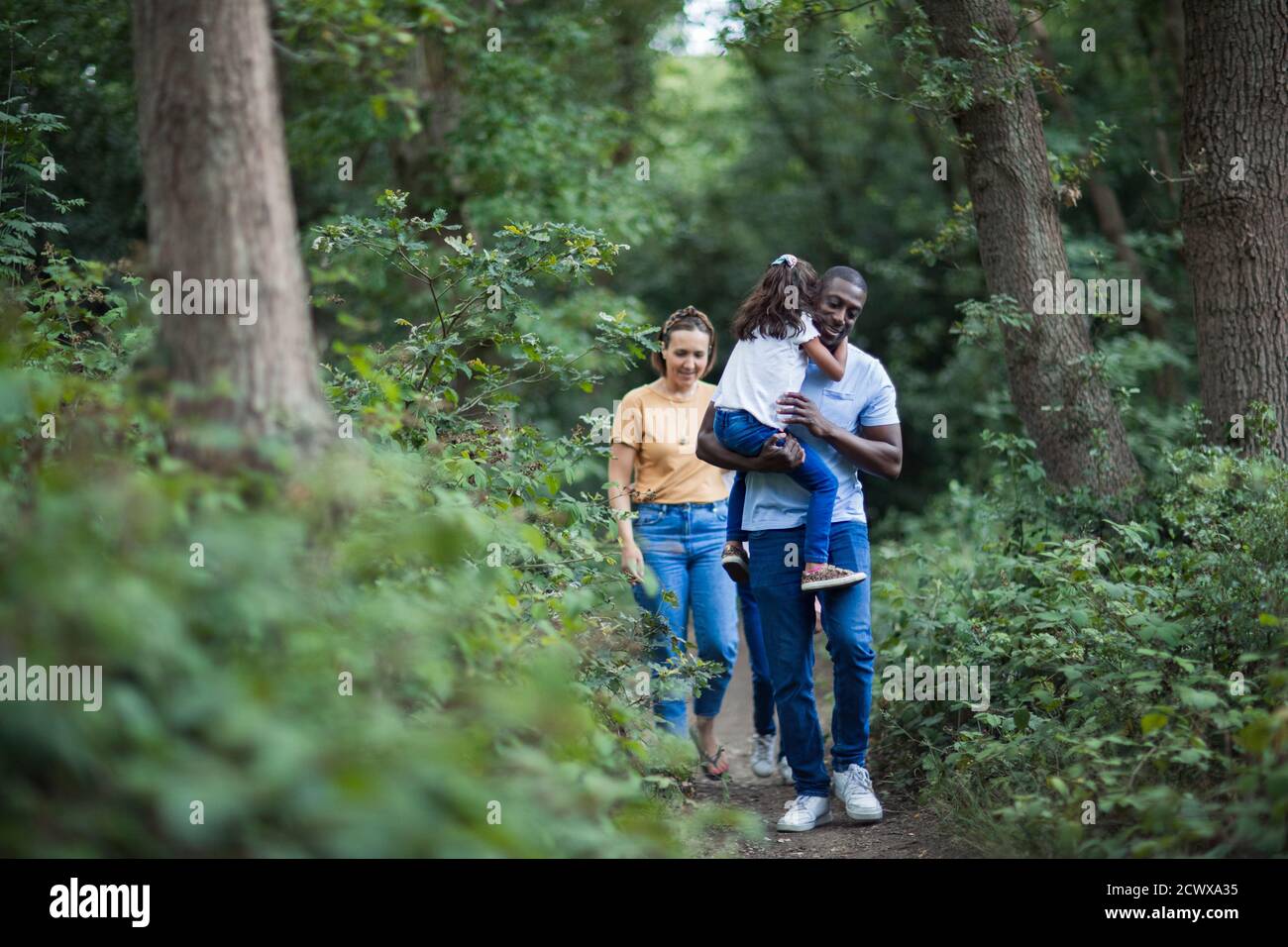 Family hiking on trail in woods Stock Photo