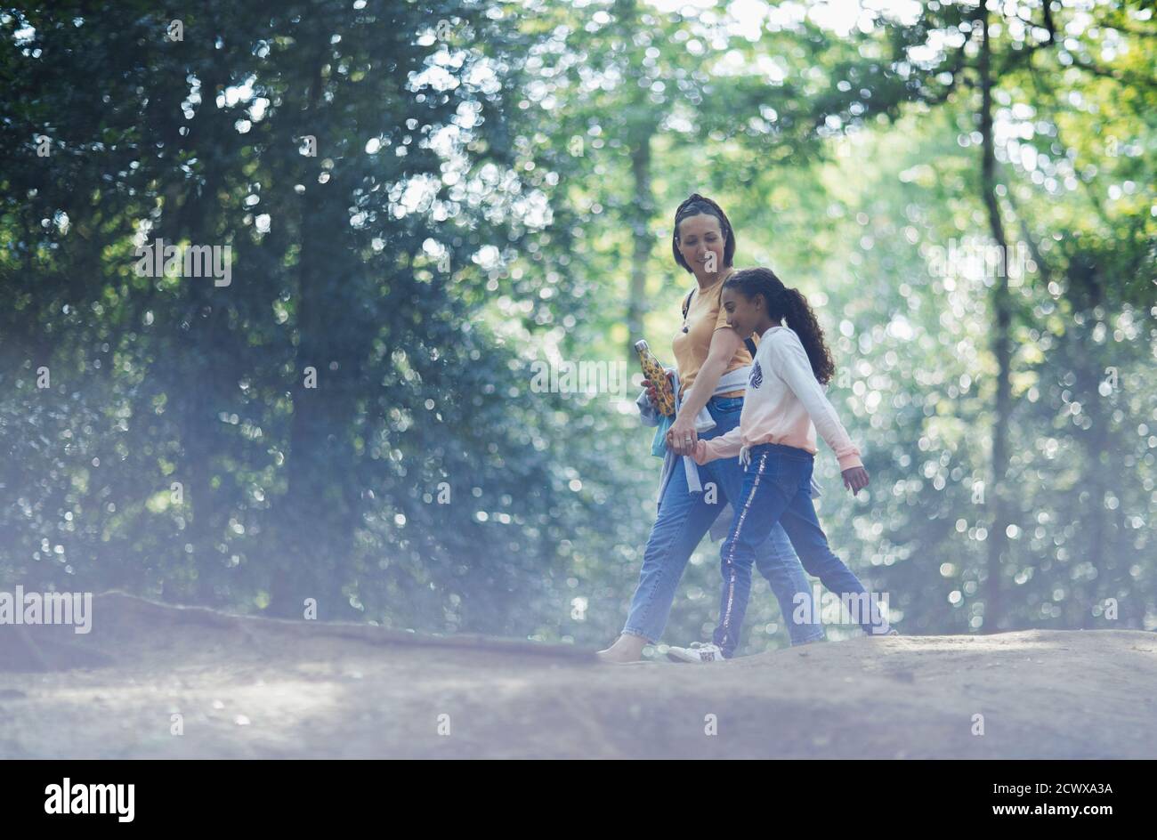 Mother and daughter holding hands hiking in summer woods Stock Photo