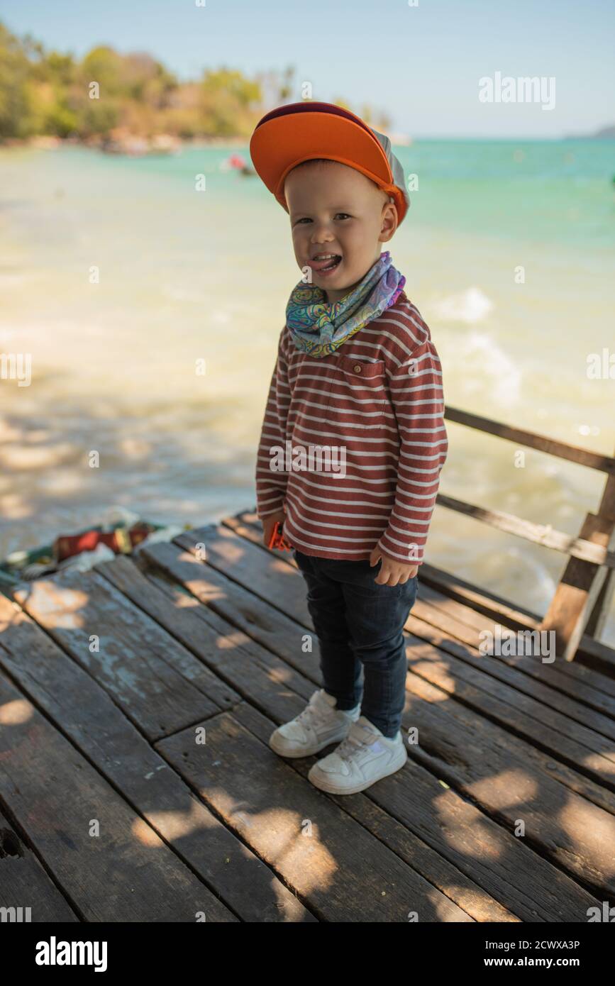 Fashion child. Happy boy model. Stylish little boy in baseball. Handsome kid. White Sneakers. red cap. Stock Photo