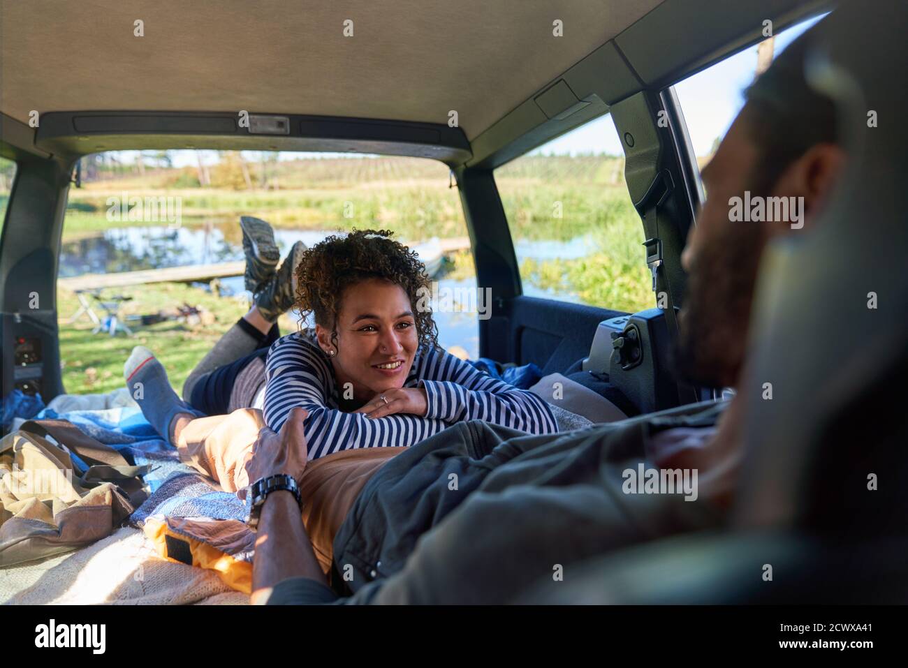 Happy young couple relaxing and camping inside back of car Stock Photo