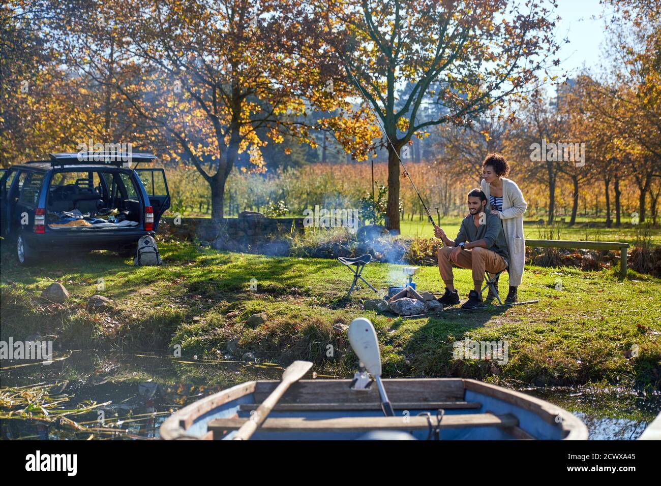 Happy young couple fishing at sunny autumn riverside Stock Photo