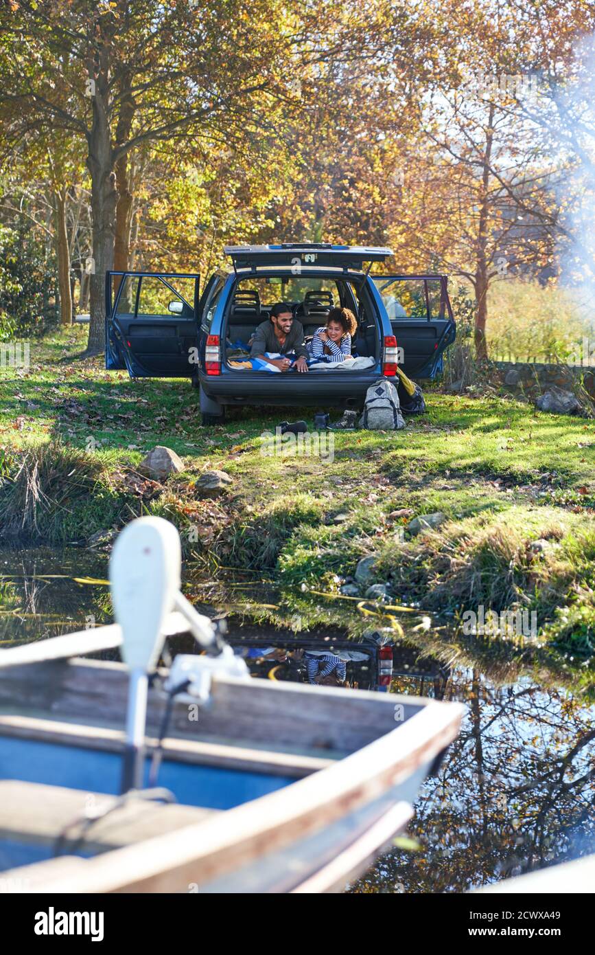 Young couple relaxing laying in back of car at sunny autumn lakeside Stock Photo