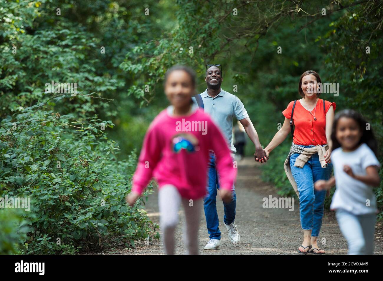 Happy family walking and running on path in woods Stock Photo